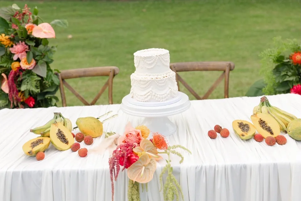 White tiered wedding cake on a tropical fruit and floral tablescape